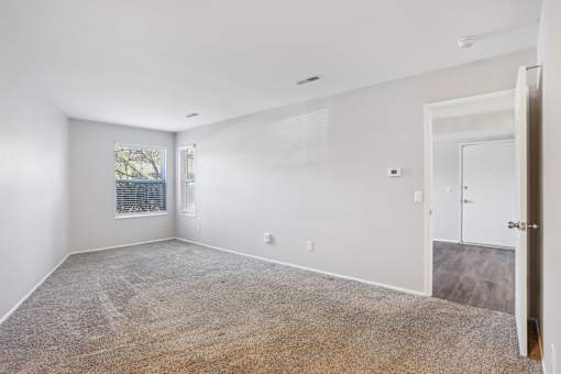 A spacious room with a carpeted floor and a door on the right side  at Millennium at Creve Coeur, Missouri