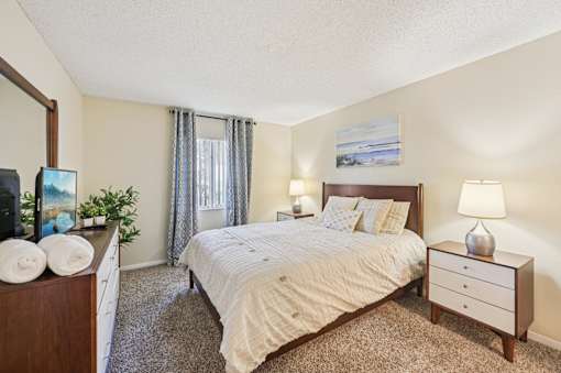 A bedroom with a large bed, a nightstand, and a dresser. at Sarasota South Apartments, Bradenton, FL, 34207