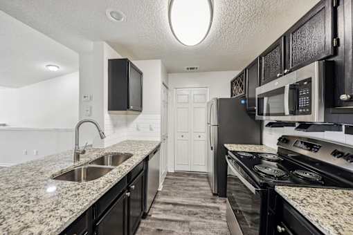 A kitchen with black cabinets and granite countertops at The Parkway at Hunters Creek, Orlando, 32837