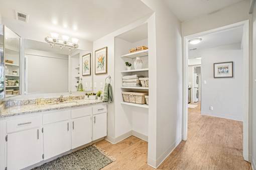 A bathroom with white cabinets and a marble countertop.