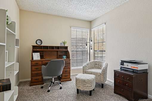 A room with a desk, chair, and printer.