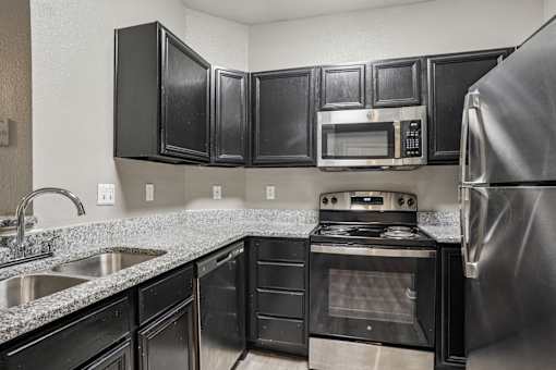 A kitchen with black cabinets and a stainless steel refrigerator at Bridford Lake Apartments, Greensboro, NC