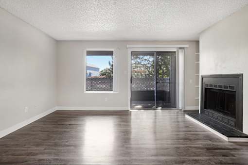 A room with a fireplace and sliding glass doors. at Windmill Apartments, Colorado Springs