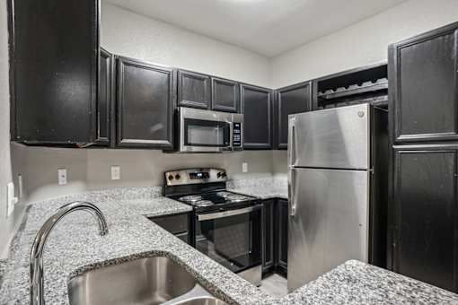 A kitchen with black cabinets and stainless steel appliances. at Bridford Lake Apartments, Greensboro, NC, 27407