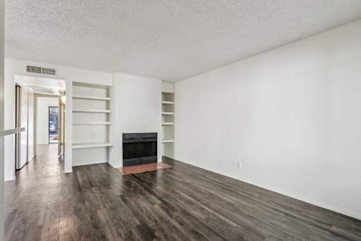 A room with a fireplace and wood flooring at Del Coronado Apartment , Mesa, AZ