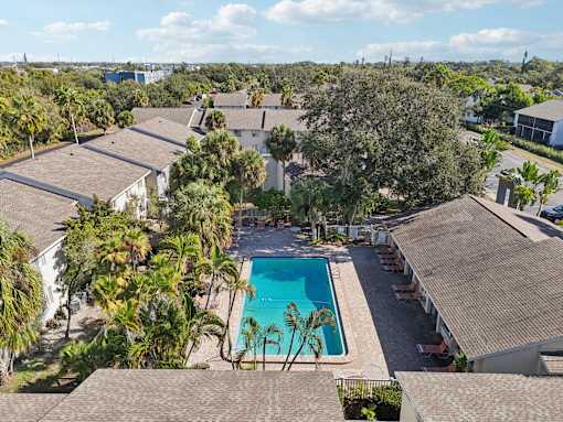 A swimming pool surrounded by palm trees and houses. at Sarasota South Apartments, Florida
