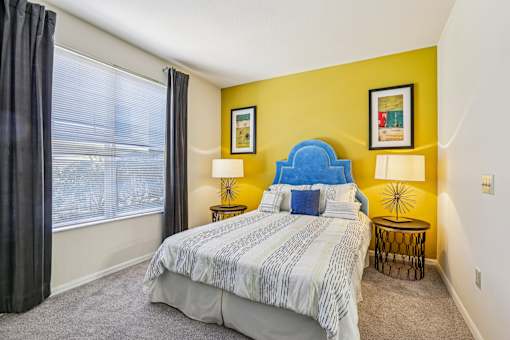 Guest bedroom with blue headboard and yellow accent wall at The Arbor Walk Apartments, Tampa, FL 33617