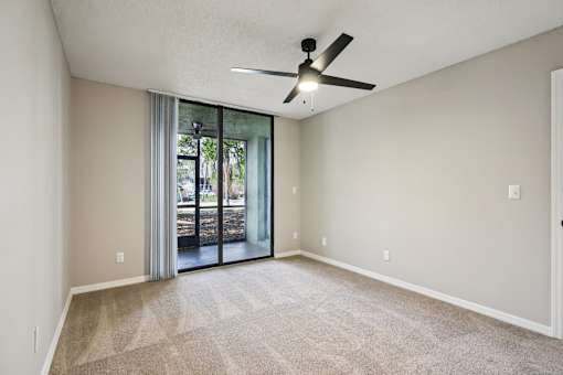 A room with a ceiling fan and sliding glass doors leading to a patio. at Lakeside Glen Apartments, Melbourne, Florida