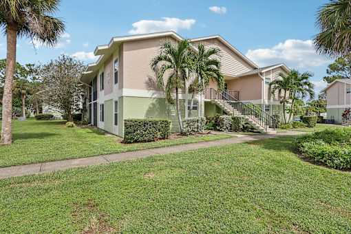 A house with a green lawn and a tree in front. at Lakeside Glen Apartments, Melbourne, FL, 32904