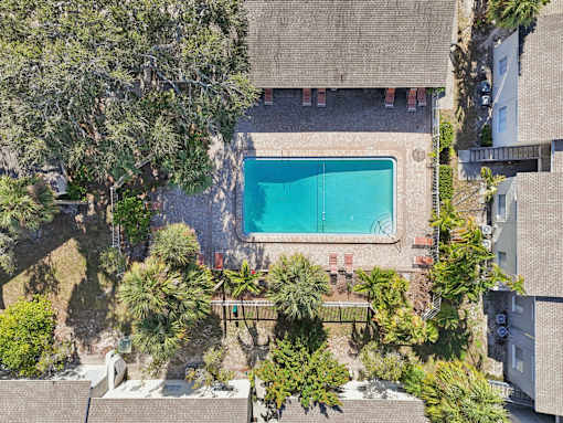 A swimming pool surrounded by trees and a building. at Sarasota South Apartments, Bradenton