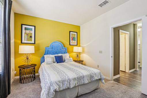 Bedroom with blue upholstered headboard and yellow wall at The Arbor Walk Apartments, Tampa, 33617