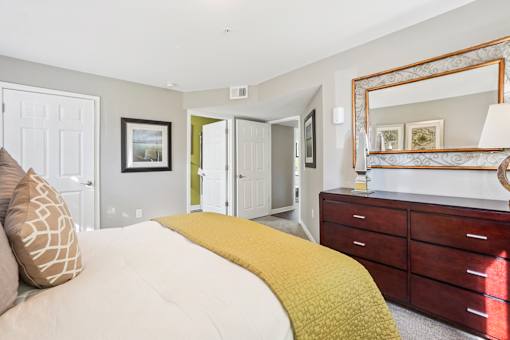 A bedroom with a bed, dresser, and mirror.
