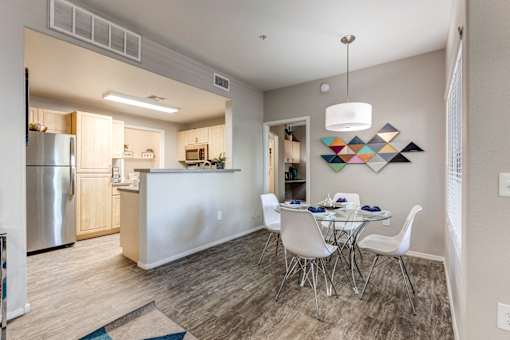 A modern kitchen with a dining table set for four at Sweetwater At Metro North Apartments, Arizona 85029