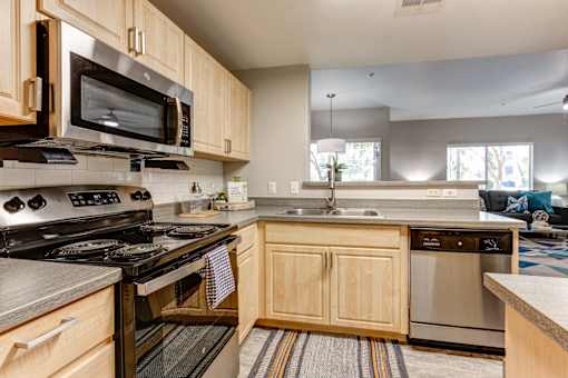 A kitchen with wooden cabinets and stainless steel appliances at Sweetwater At Metro North Apartments, Phoenix, Arizona