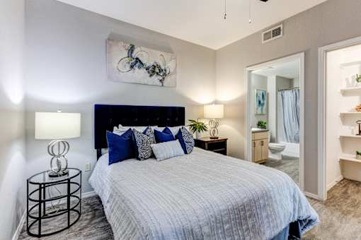 A bedroom with a bed, nightstand, and a painting on the wall at Sweetwater At Metro North Apartments, Arizona