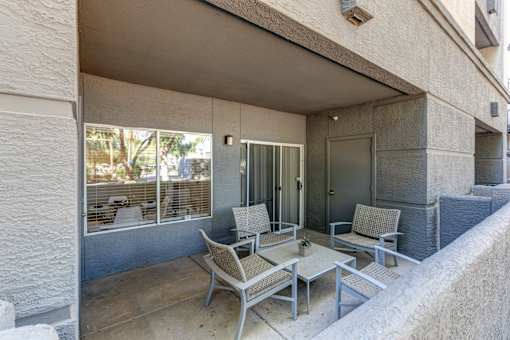 A patio with a table and chairs is on the balcony of a building at Sweetwater At Metro North Apartments, Phoenix
