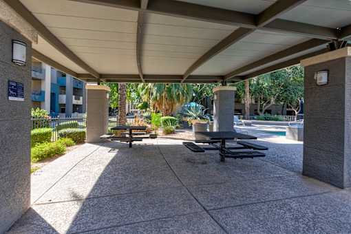 A concrete patio with a table and chairs under a roof at Sweetwater At Metro North Apartments, Phoenix