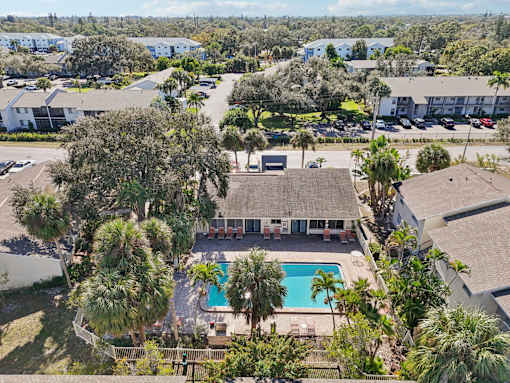 A swimming pool is surrounded by palm trees and a building. at Sarasota South Apartments, Bradenton, Florida
