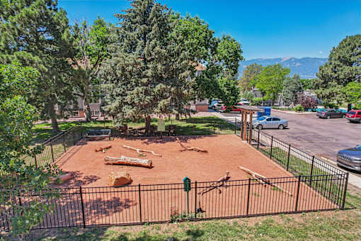 A playground with a red surface and a black fence.