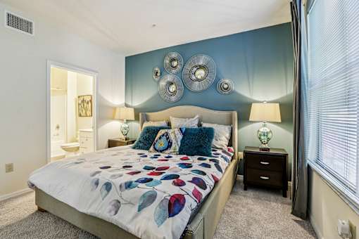 Master bedroom with teal accent wall and ensuite bathroom at The Arbor Walk Apartments, Tampa