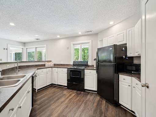 A kitchen with black appliances and white cabinets. at University Ridge Apartments, Durham, 27707