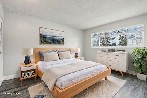 A bedroom with a large bed, a nightstand with a lamp, and a painting on the wall. at Spyglass Creek, Denver, 80224