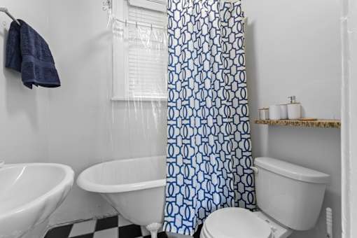 A white toilet sits next to a white sink in a bathroom with a blue and white shower curtain.at The Collection of Historic Richmond, Richmond Virginia