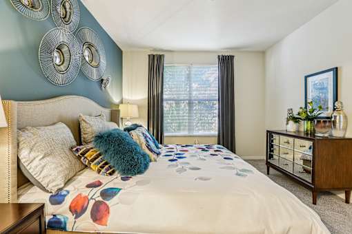 Spacious bedroom with colorful bedding and mirrored dresser at The Arbor Walk Apartments, Florida