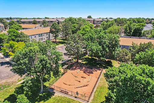 A tennis court surrounded by trees and buildings.