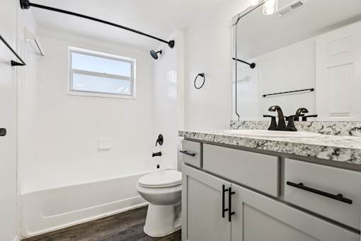 A white toilet sits in a bathroom with a marble counter. at Lakeside Glen Apartments, Melbourne, FL, 32904