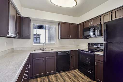 A kitchen with dark brown cabinets and black appliances at Del Coronado Apartment , Mesa, 85202