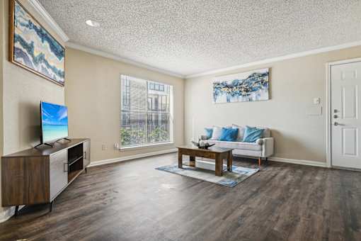 a living room with a couch and a table and a tv at The Glen at Highpoint, Dallas, 75243