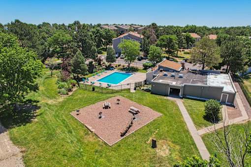 A large grassy area with a pool and a building in the background.