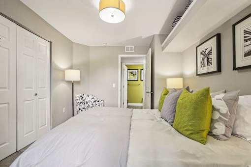 A bedroom with a white bed and green pillows.