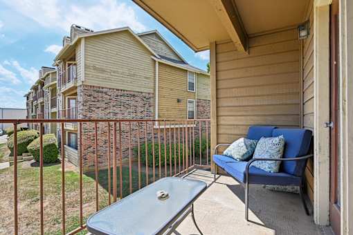 A patio with a blue cushioned chair and a table.