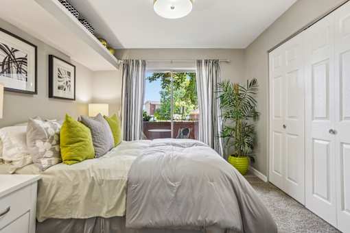 A bedroom with a bed, pillows, and a window with curtains.