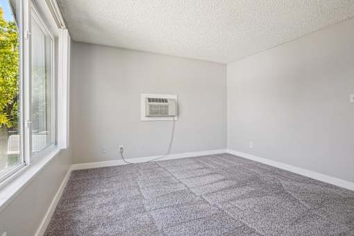 A room with a window and a carpet on the floor. at Windmill Apartments, Colorado Springs, CO, 80916