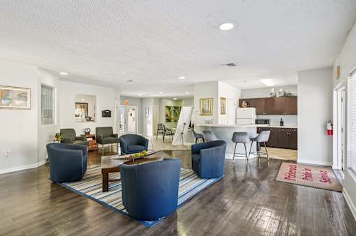 A living room with a blue rug and a brown wooden floor. at Sarasota South Apartments, Bradenton, FL