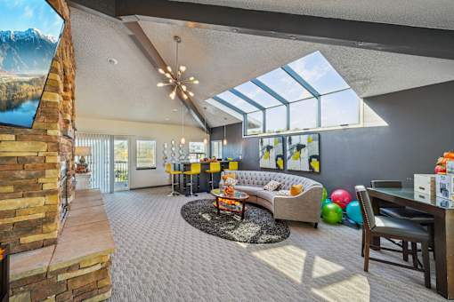 A living room with a stone fireplace and a skylight at Union Heights Apartments, Colorado Springs, Colorado