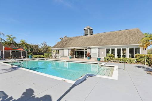 Community pool with clubhouse and surrounding deck at The Arbor Walk Apartments, Tampa, 33617