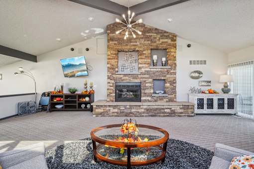 A modern living room with a stone fireplace and a television mounted on the wall at Union Heights Apartments, Colorado Springs, Colorado