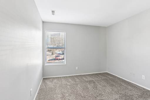 A room with a carpeted floor and a window with blinds. at Millennium at Creve Coeur, Creve Coeur