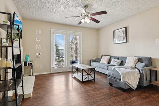 A living room with a grey couch and a ceiling fan.