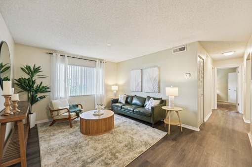 A living room with a green couch, a wooden coffee table, and a rug. at Sarasota South Apartments, Florida, 34207
