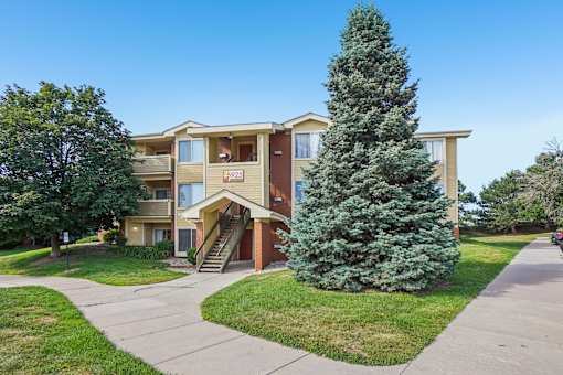 A large tree is in front of a two-story apartment building.