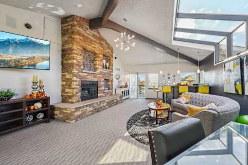 A living room with a stone fireplace and a flat screen TV mounted on the wall at Union Heights Apartments, Colorado Springs, Colorado