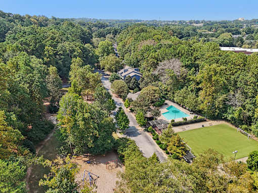 A bird's eye view of a lush green forest with a swimming pool and a playground. at Canopy Glen, Norcross, Georgia