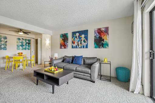 A living room with a grey couch, a yellow dining table, and a painting on the wall at Spyglass Creek, Denver, 80224