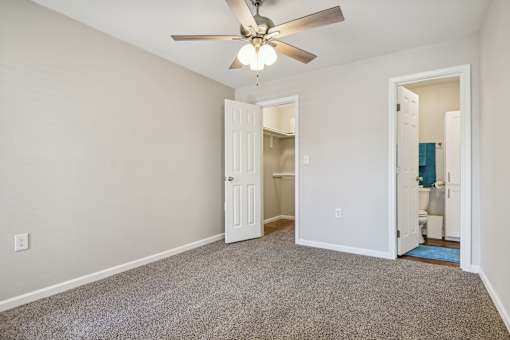 a bedroom with a ceiling fan and a door to a bathroom at The Glen at Highpoint, Dallas, 75243