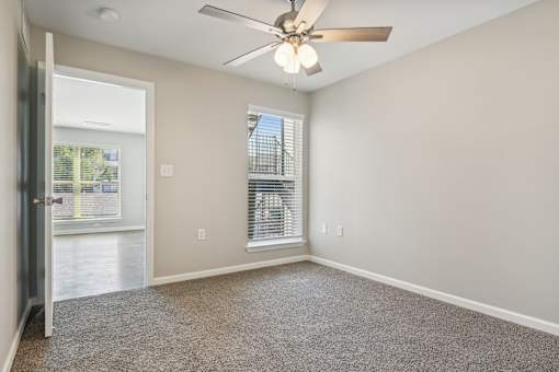 an empty living room with a ceiling fan and a window at The Glen at Highpoint, Dallas, 75243